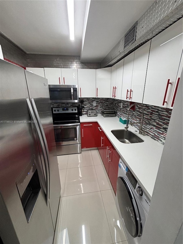 1200 W Ave Unit 209, Miami Beach, FL 33139 - kitchen featuring stainless steel appliances, washer / dryer, a sink, tasteful backsplash, and light tile patterned floors