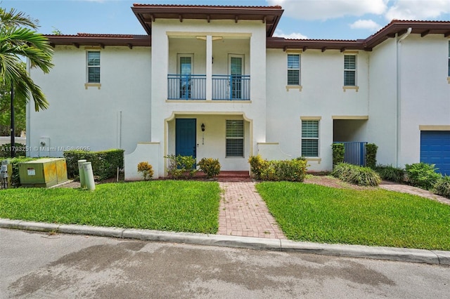 view of front of home with stucco siding, a front lawn, and a balcony