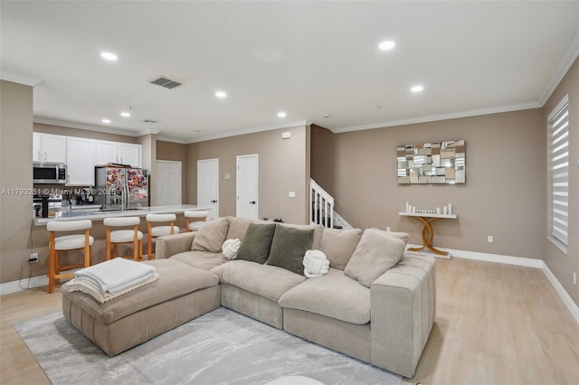living room with light wood finished floors, crown molding, visible vents, and recessed lighting