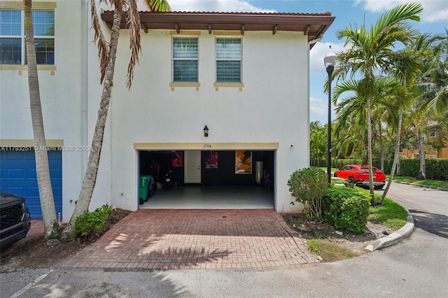 view of front facade featuring a garage, stucco siding, and decorative driveway