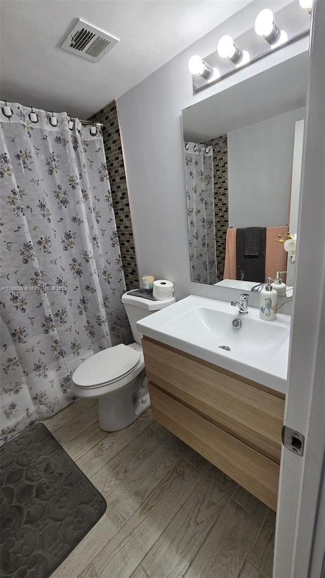 full bath featuring toilet, vanity, visible vents, and curtained shower