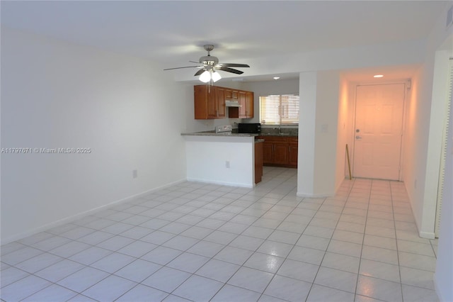 kitchen with electric range oven, baseboards, ceiling fan, and brown cabinets