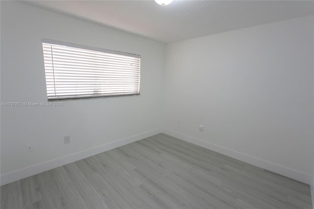 spare room with light wood finished floors and baseboards