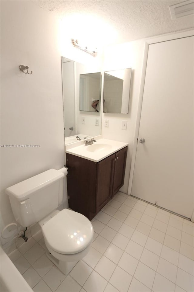 bathroom featuring toilet, vanity, a textured ceiling, visible vents, and tile patterned flooring