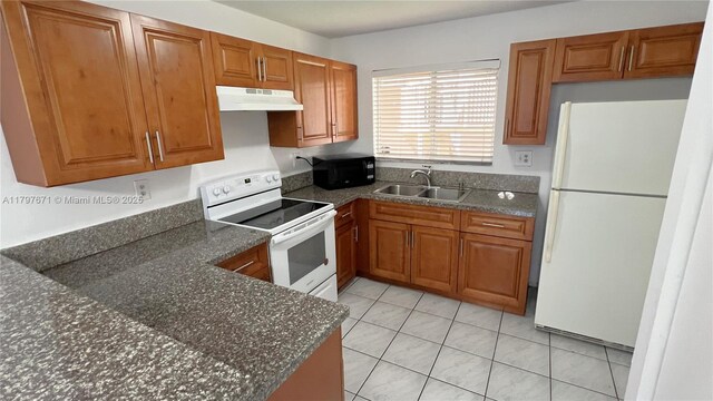 kitchen featuring brown cabinetry, white appliances, under cabinet range hood, and a sink