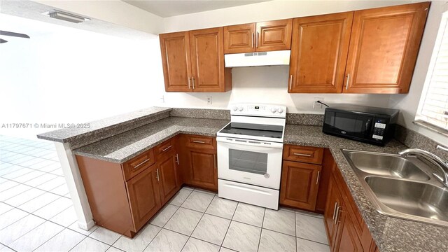 kitchen with a sink, a peninsula, under cabinet range hood, black microwave, and white range with electric cooktop