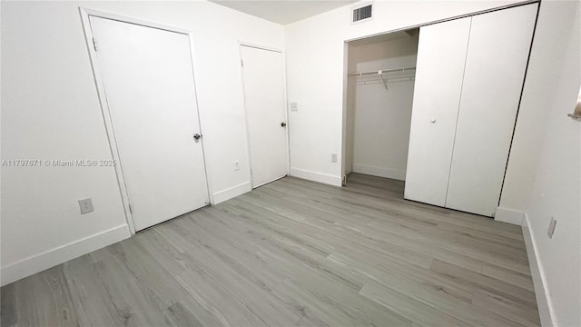 unfurnished bedroom with baseboards, light wood-style flooring, and visible vents
