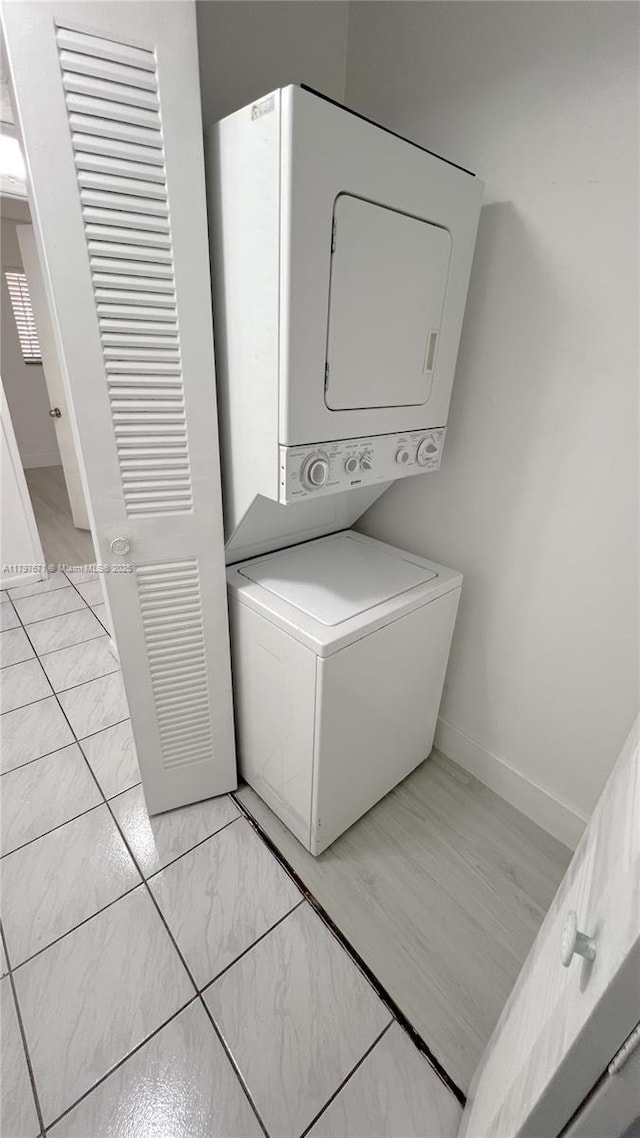 laundry area featuring laundry area, stacked washer and dryer, and baseboards