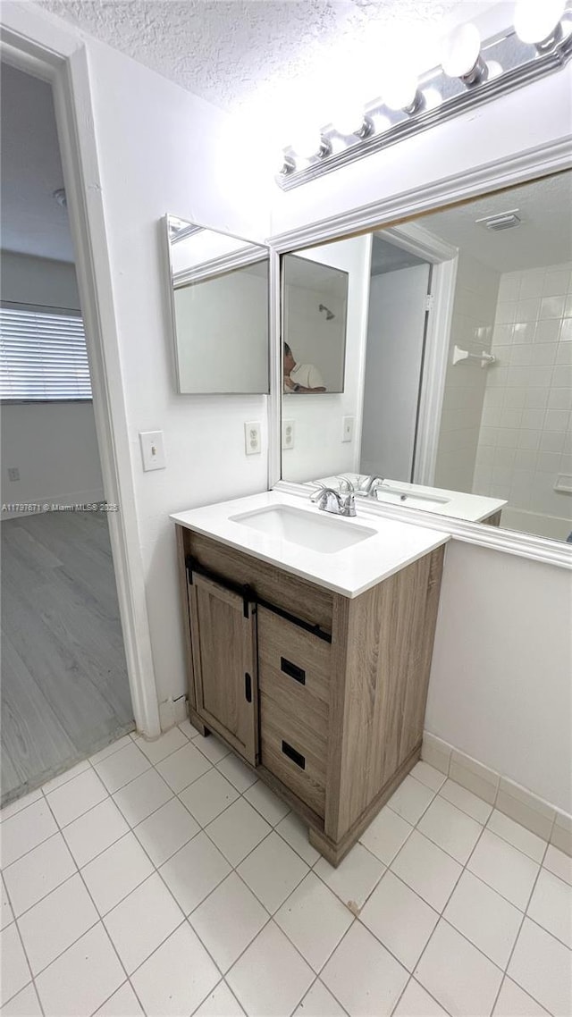 bathroom with vanity, a textured ceiling, baseboards, and tile patterned floors