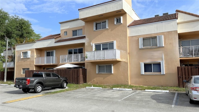 view of building exterior with fence and uncovered parking