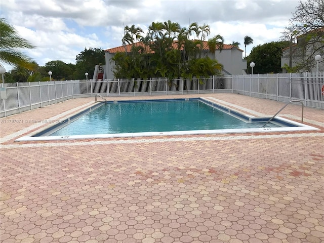 pool with a patio area and fence