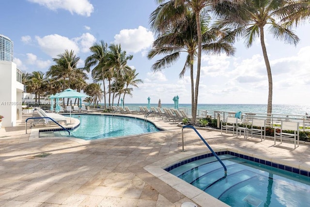 community pool with a water view, a patio area, a hot tub, and a gazebo