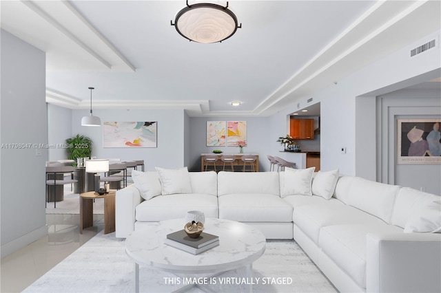living area with baseboards, a tray ceiling, and visible vents
