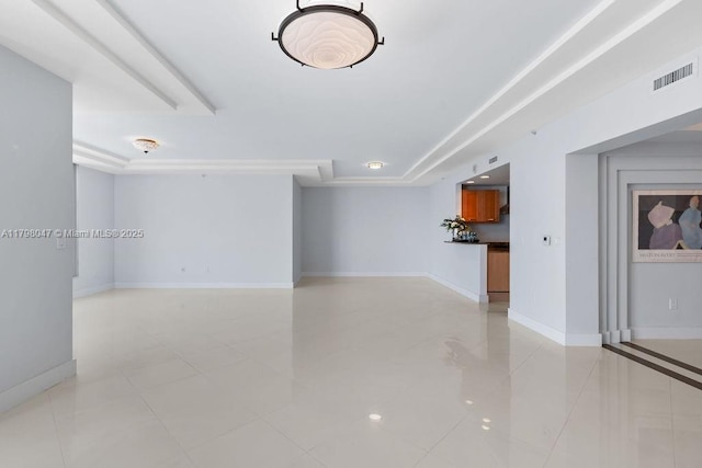 unfurnished living room featuring a tray ceiling, light tile patterned flooring, baseboards, and visible vents