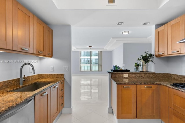 kitchen featuring light tile patterned floors, dishwashing machine, dark stone countertops, and a sink