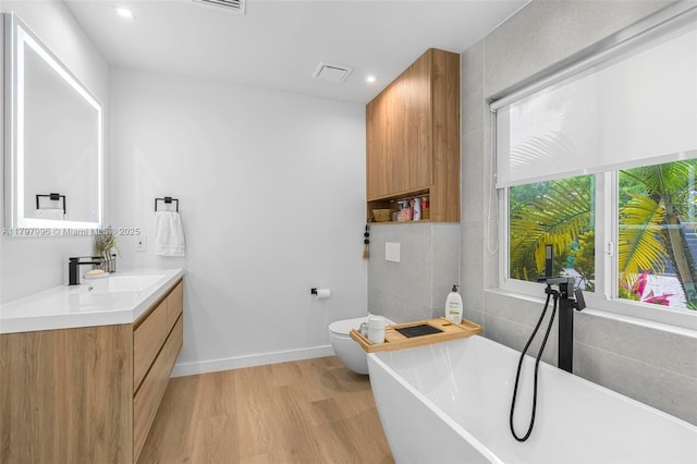 7560 SW 144th St, Palmetto Bay, FL 33158 - bathroom with toilet, wood finished floors, vanity, a soaking tub, and baseboards