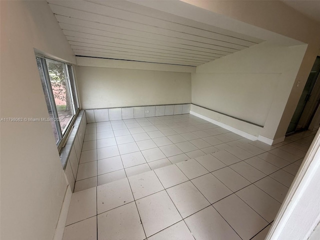 spare room with vaulted ceiling, wooden ceiling, and light tile patterned floors