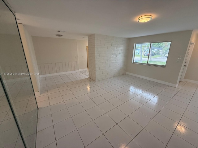 spare room featuring light tile patterned floors and baseboards