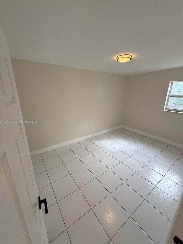spare room with light tile patterned flooring and baseboards