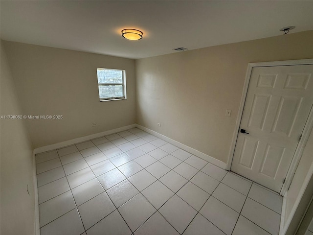 empty room featuring light tile patterned floors, baseboards, and visible vents