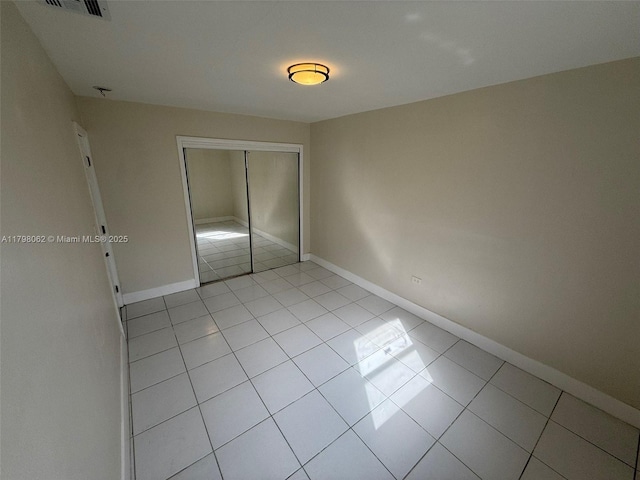 unfurnished bedroom featuring a closet, baseboards, light tile patterned floors, and visible vents