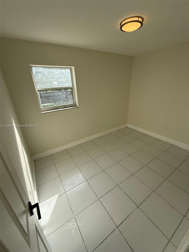 tiled spare room featuring baseboards
