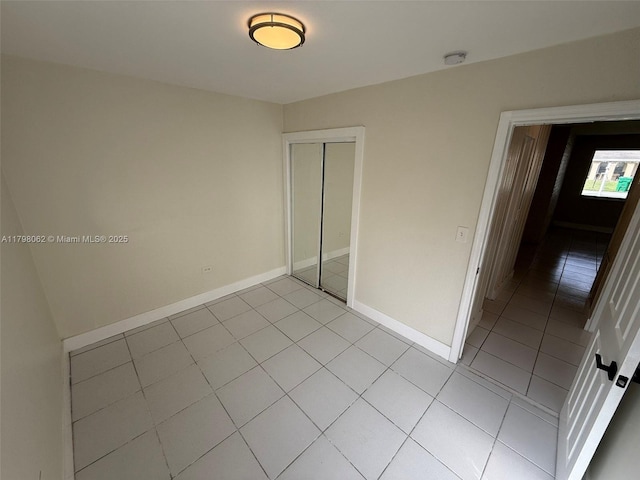 unfurnished bedroom with a closet, baseboards, and light tile patterned floors