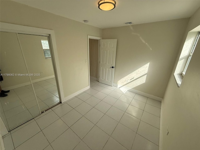 unfurnished bedroom with a closet, visible vents, tile patterned flooring, and baseboards