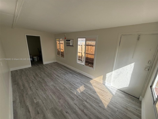 unfurnished room featuring wood finished floors, baseboards, and a wall mounted AC