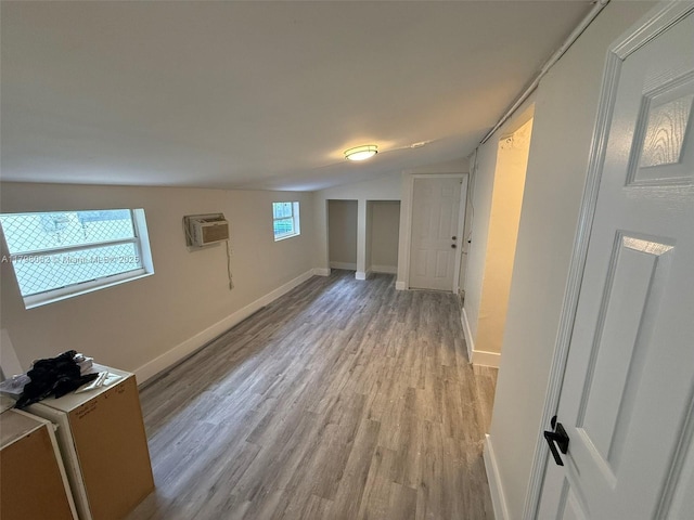basement featuring light wood finished floors, baseboards, and a wall mounted AC