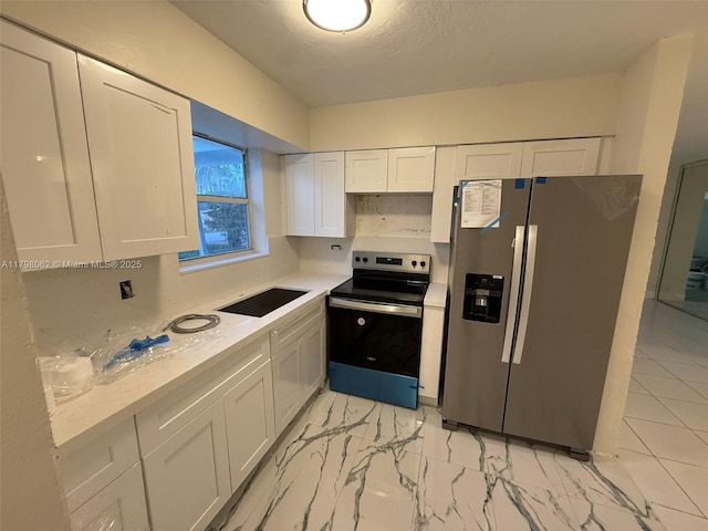 kitchen with a sink, stainless steel appliances, white cabinetry, light countertops, and marble finish floor