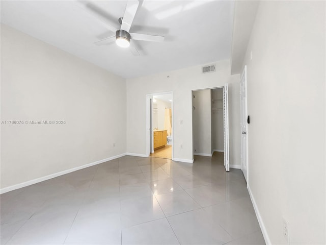unfurnished bedroom featuring baseboards, light tile patterned floors, ensuite bathroom, ceiling fan, and visible vents