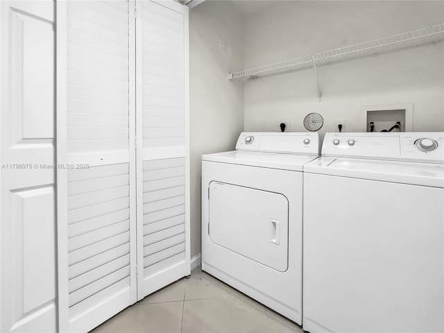 clothes washing area with washing machine and dryer, light tile patterned floors, and laundry area