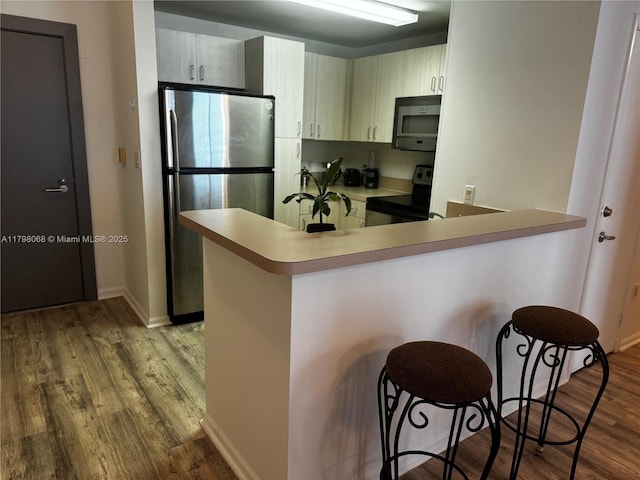 185 SE 14th Ter Unit 1812, Miami, FL 33131 - kitchen featuring stainless steel appliances, wood finished floors, a peninsula, a kitchen bar, and baseboards