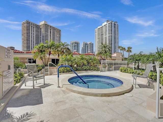 view of pool with a hot tub, a patio area, and a view of city