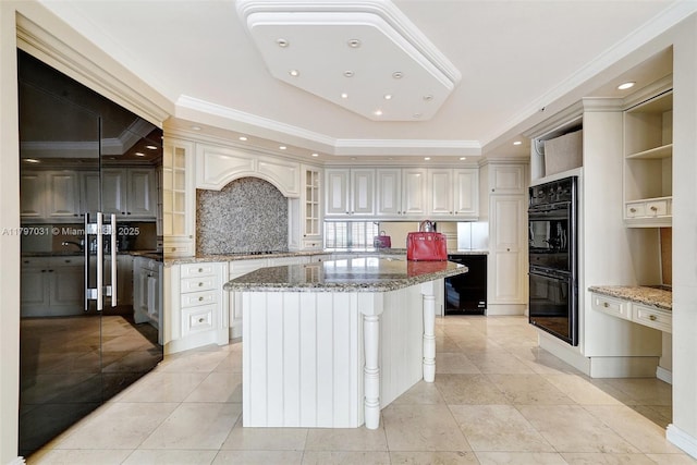 19667 Turnberry Way Unit 16Gr, Aventura, FL 33180 - kitchen with black appliances, crown molding, a kitchen island, tasteful backsplash, and light stone counters