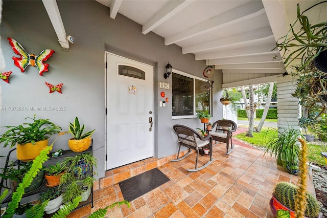 property entrance featuring a porch and stucco siding