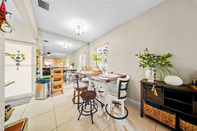 dining area with baseboards, tile patterned floors, visible vents, and a textured ceiling
