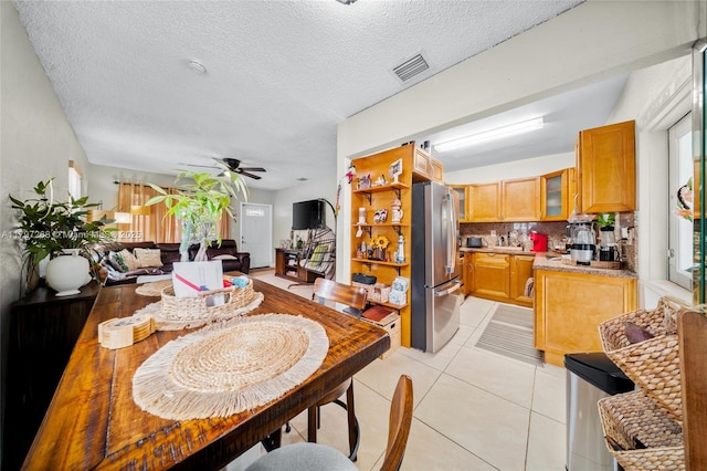 dining space featuring a ceiling fan, light tile patterned floors, visible vents, and a textured ceiling