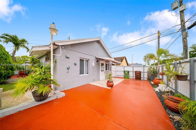 rear view of property featuring a patio area, stucco siding, and a fenced backyard