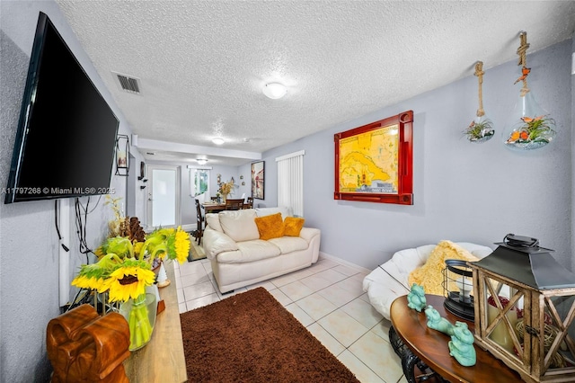 tiled living area featuring a textured ceiling, baseboards, and visible vents