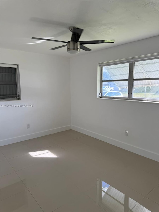 empty room featuring baseboards, a ceiling fan, and tile patterned flooring