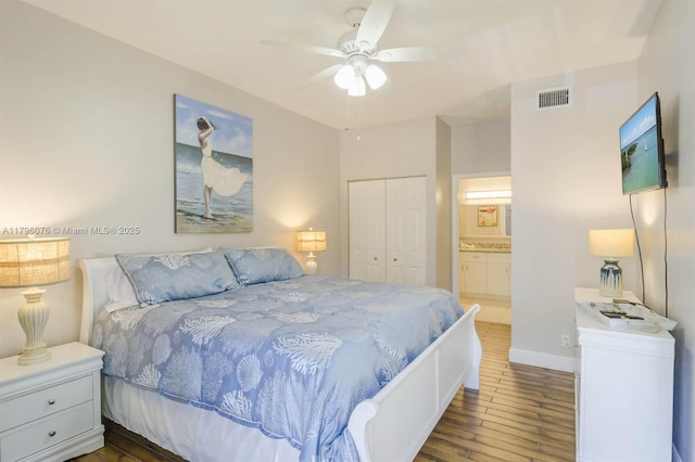 bedroom featuring a closet, ensuite bathroom, ceiling fan, visible vents, and wood finished floors