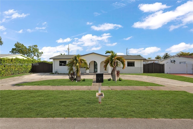 ranch-style home with a front lawn, curved driveway, fence, and a gate