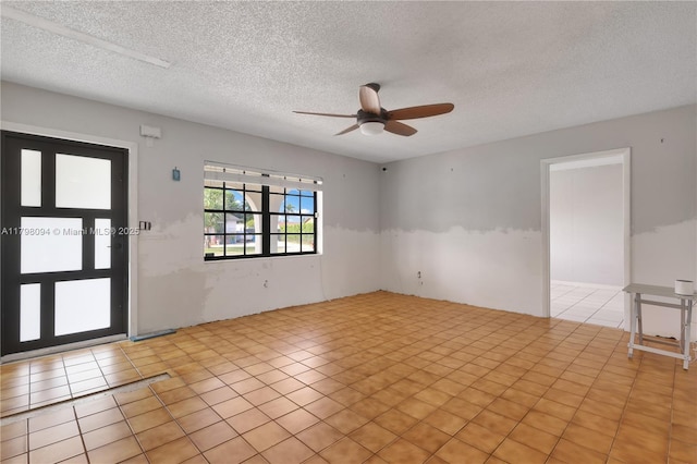 spare room with light tile patterned floors, a textured ceiling, and a ceiling fan