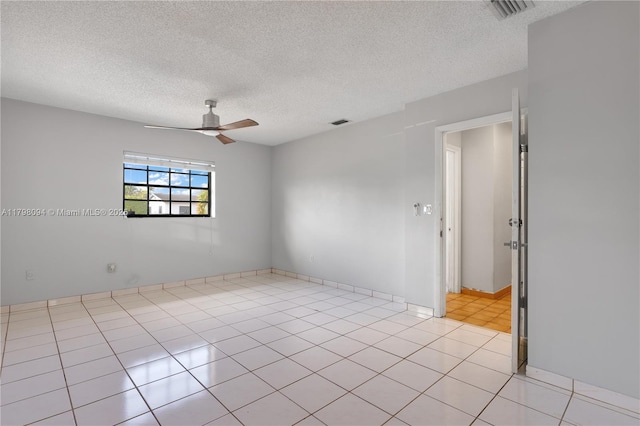 spare room with light tile patterned floors, a textured ceiling, visible vents, and a ceiling fan