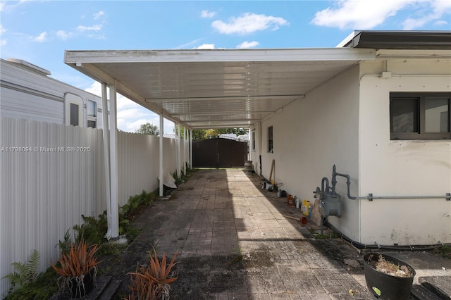 view of patio with a carport, fence, and a storage unit