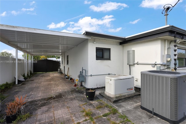 exterior space featuring central AC unit, fence, stucco siding, and an attached carport