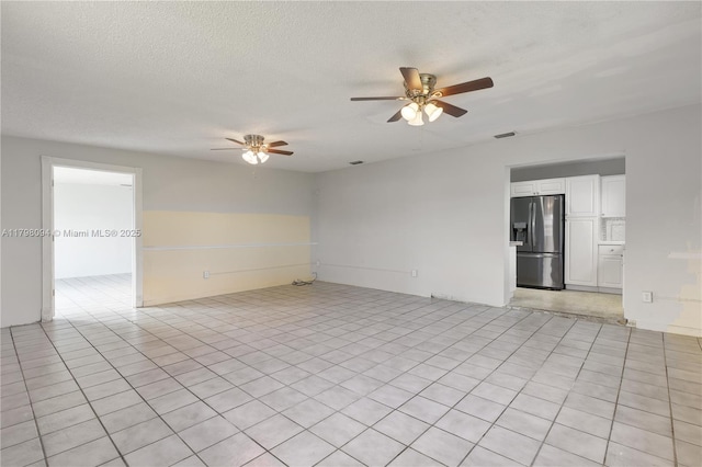 empty room with ceiling fan and a textured ceiling
