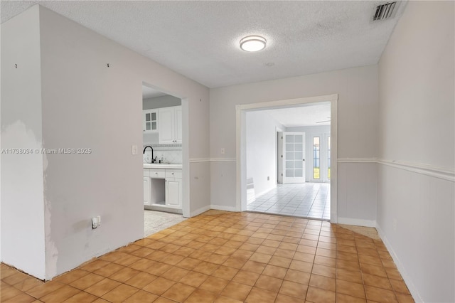 spare room with a textured ceiling, light tile patterned floors, and a sink